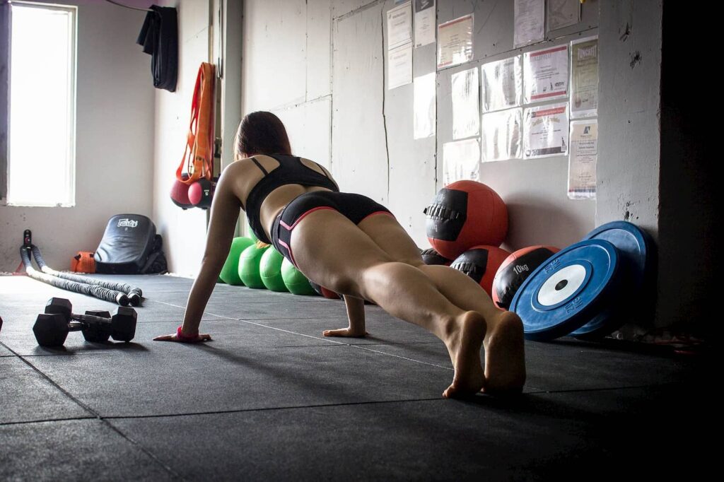 Mujer haciendo una plancha en gimnasio.